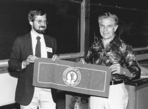 At a ceremony at a meeting of the Astronomical Society of the Pacific, Karl Henize presents the Society's banner, which flew in space in his personal kit aboard the Space Shuttle, to Andrew Fraknoi.